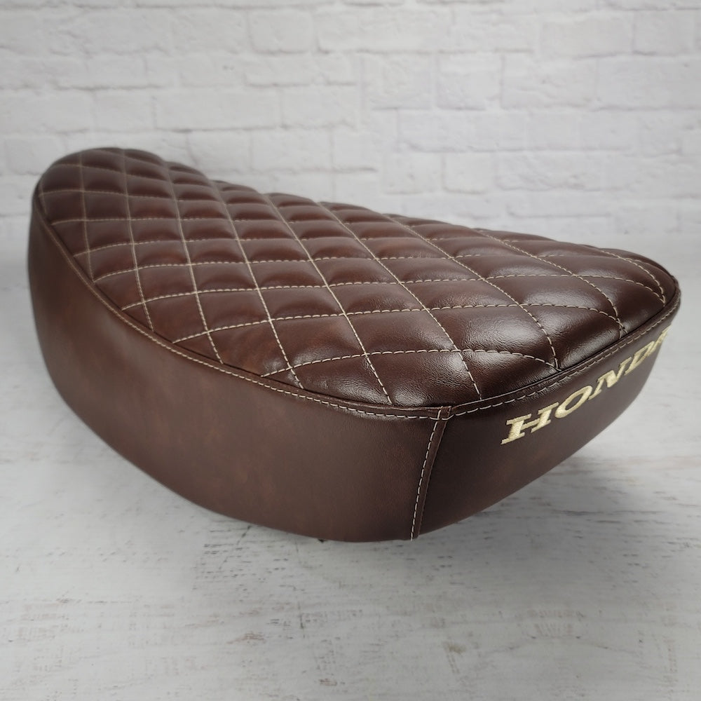 Rear three-quarter view of a whiskey brown diamond stitched Honda DAX 125 seat cover with cream stitching and Honda embroidery, handmade by Cheeky Seats