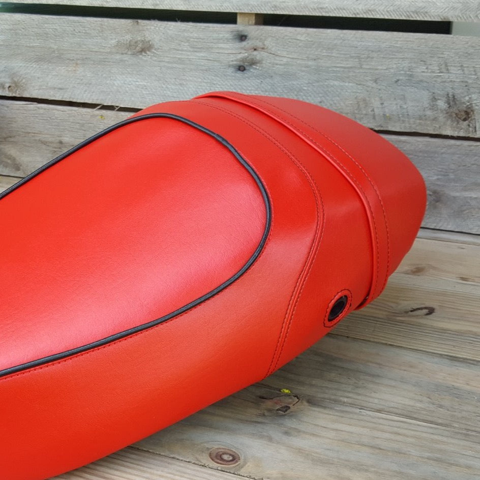 Close-up of red Vespa S seat cover with black piping, red stitching and matching red strap by Cheeky Seats