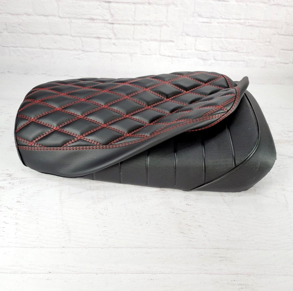 Matte black diamond-stitched seat cover with red contrast stitching, shown installed on the original Maddog seat