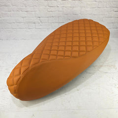 Brown quilted leather seat on a white brick background