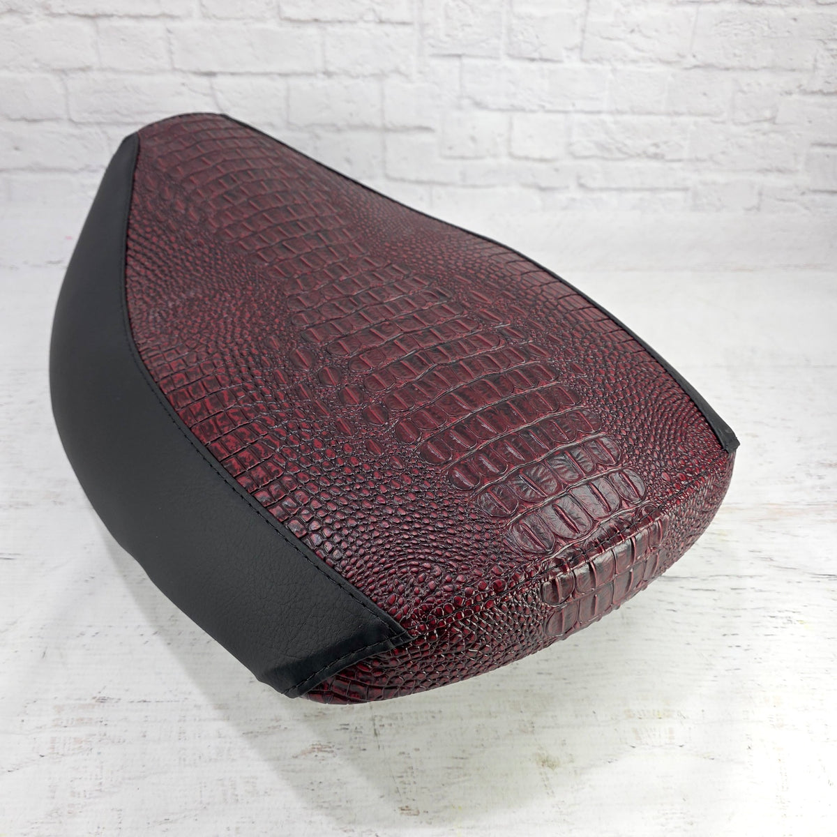 Angled view of the Ruby Garnet Gator Yamaha Vino 125 seat cover showing the embossed center panel and tailored black sides, handmade by Cheeky Seats.